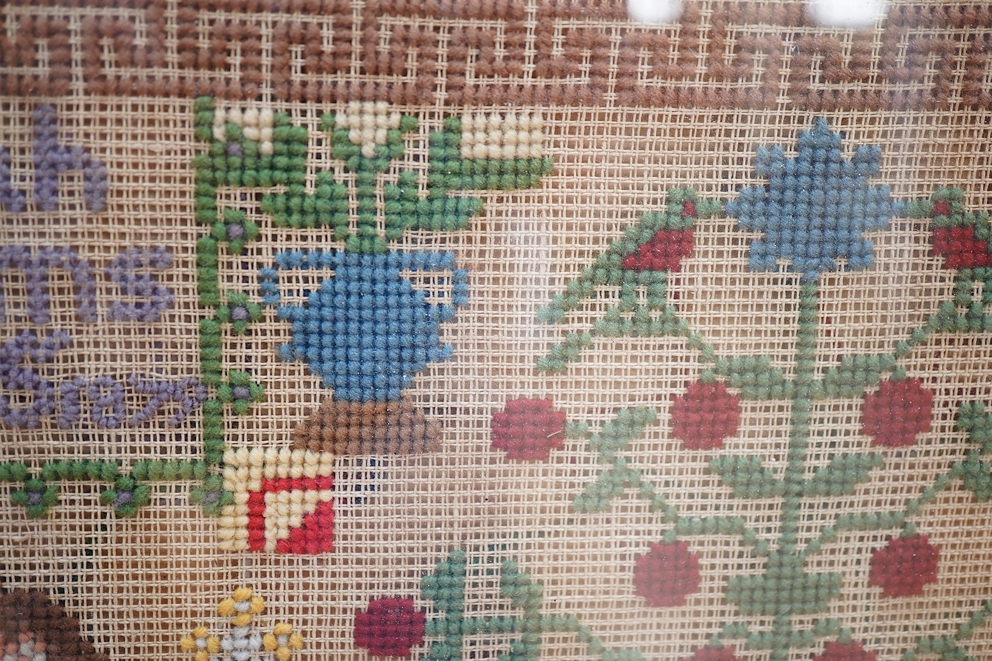 A 19th century cross stitch sampler by Mariah Williams age 15 dated 1879, worked with an outer geometric border, with rows of various alphabet letters and numerals., the lower half with large spot motifs of flowers, tree